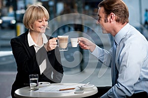 Business partners toasting coffee at cafe