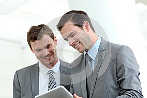 Business partners using tablet in hallway