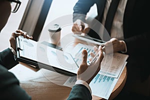 Business partnership coworkers using a tablet to chart company financial statements report and profits work progress and planning