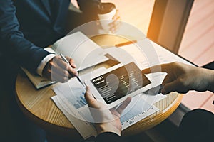 Business partnership coworkers using a tablet to chart company financial statements report and profits work progress and planning