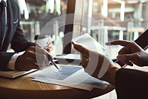 Business partnership coworkers using a tablet to chart company financial statements report and profits work progress and planning