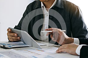 Business partnership coworkers using a tablet to chart company financial statements report and profits work progress and planning