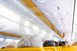 Business passenger on a plane requesting assistance from stewardesses, raising his hand to press the help button