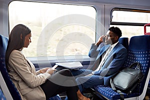 Business Passengers Sitting In Train Commuting To Work Using Mobile Phones