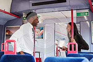 Business Passengers Standing In Train Commuting To Work Having Discussion
