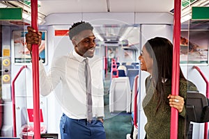 Business Passengers Standing In Train Commuting To Work Having Discussion