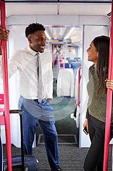 Business Passengers Standing In Train Commuting To Work Having Discussion