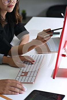 Business people analyzing business data on computer together in office.