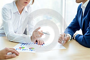 Business People Analyzing Financial Results on Graphs around the Table in Modern Office. Team Work Concept