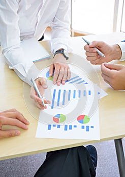 Business People Analyzing Financial Results on Graphs around the Table in Modern Office. Team Work Concept