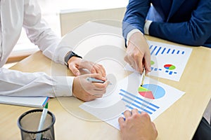 Business People Analyzing Financial Results on Graphs around the Table in Modern Office. Team Work Concept