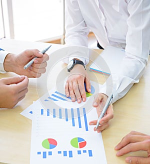 Business People Analyzing Financial Results on Graphs around the Table in Modern Office. Team Work Concept