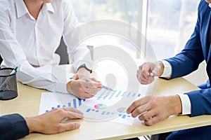 Business People Analyzing Financial Results on Graphs around the Table in Modern Office. Team Work Concept