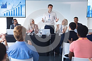 Business people applauding male speaker in business seminar