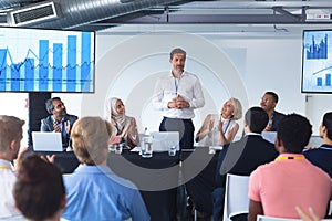 Business people applauding male speaker at table in business seminar