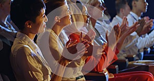 Business people applauding while sitting on seats in auditorium 4k