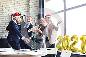 Business people are celebrating holiday in modern office drinking champagne and having fun in coworking. New Year 2021