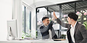 Business people celebrating success in an office. Business team giving a high five to a colleague in meeting.