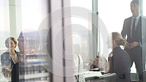 Business people clapping to colleague in conference room, behind glass wall