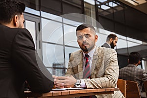 Business people colleagues sit at a table on the street and talk. Business team and brainstorming. Interaction and