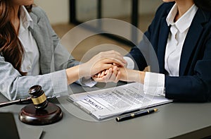 Business people compassionately holding hands and discussing contract papers with laptop and tablet at office