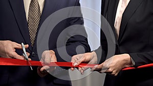 Business people cutting red ribbon with scissors, start-up and collaboration