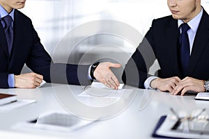 Business people discuss a contract, sitting at the desk in a modern office. Unknown businessman with a colleague