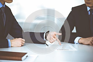 Business people discuss a contract, sitting at the desk in a modern office. Unknown businessman with a colleague
