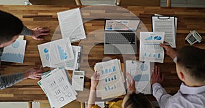 Business people discuss financial report in charts and graphs top view