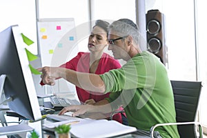 Business people discussing over computer at desk in office