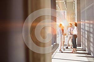 Business people discussing plans before meeting in office hall with yellow lens flare in background