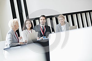 Business people discussing while sitting at desk in seminar hall