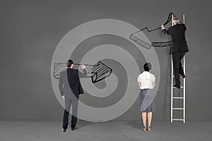 Business people drawing black arrows in a grey background