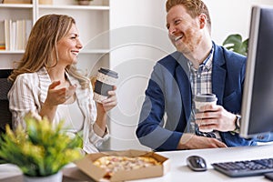 Business people eating pizza and drinking coffee while on a lunch break