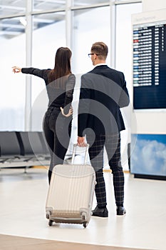 Business people in formal clothing walking with wheeled bags at airport terminal