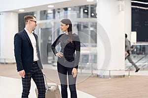 Business people in formal clothing walking with wheeled bags at airport terminal