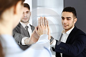 Business people group showing teamwork, joining hands and giving five to each other in modern office. Success concept