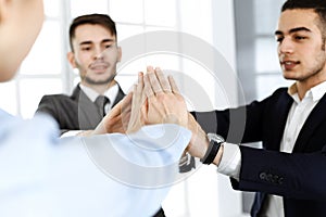 Business people group showing teamwork, joining hands and giving five to each other in modern office. Success concept