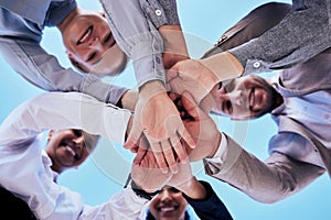 Business people, hands together and teamwork in unity below blue sky for agreement or collaboration outdoors. Group of