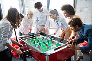 Business people having great time together.Colleagues playing table football in office.
