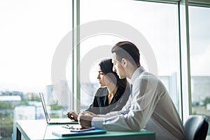 Business people Having Meeting Around Table In Modern Office against windows.