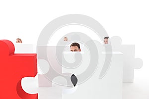 Business people hiding behind puzzle