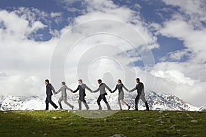 Business People Holding Hands And Walking Through Mountains