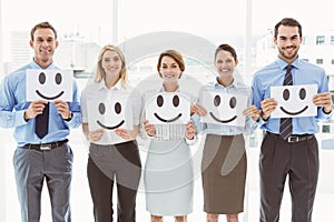 Business people holding happy smileys in office