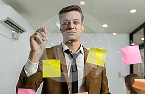 Business people holding pen and put sticky notes on glass wall in office. business people meeting at office and use post it notes