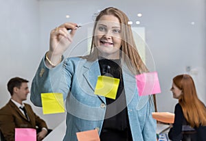 Business people holding pen and put sticky notes on glass wall in office. business people meeting at office and use post it notes