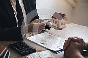 Business people home sales broker is using a pen pointing to the house model and describing the various components of the house
