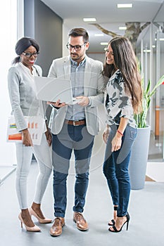 Business people with laptop and documents discussing project in office hall