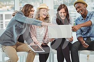 Business people laughing while pointing at laptop