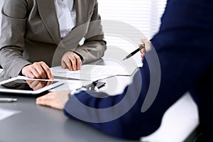 Business people and lawyer discussing contract papers sitting at the table, hands close-up. Teamwork or group operations